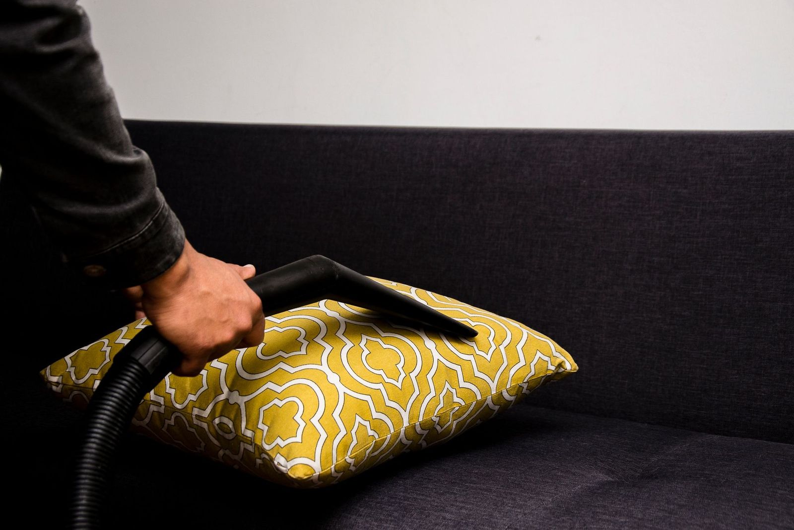 Absaugen eines gemusterten Kissens auf einem dunklen Sofa